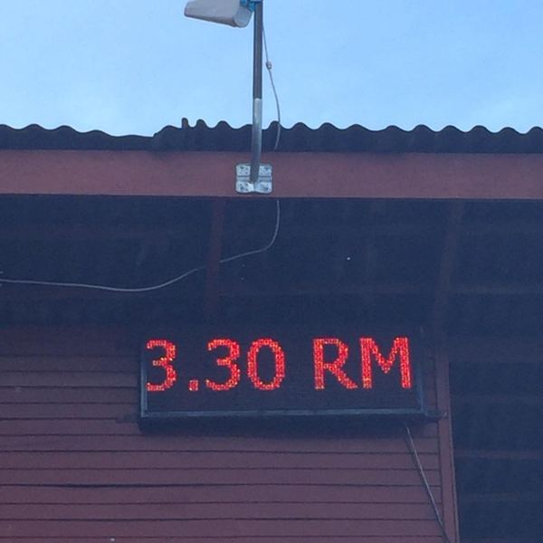 Directional outdoor antenna mounted on a pole above an illuminated LED price display